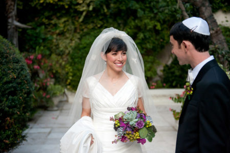 Sephardic bride with veil and flowers with groom looking at her