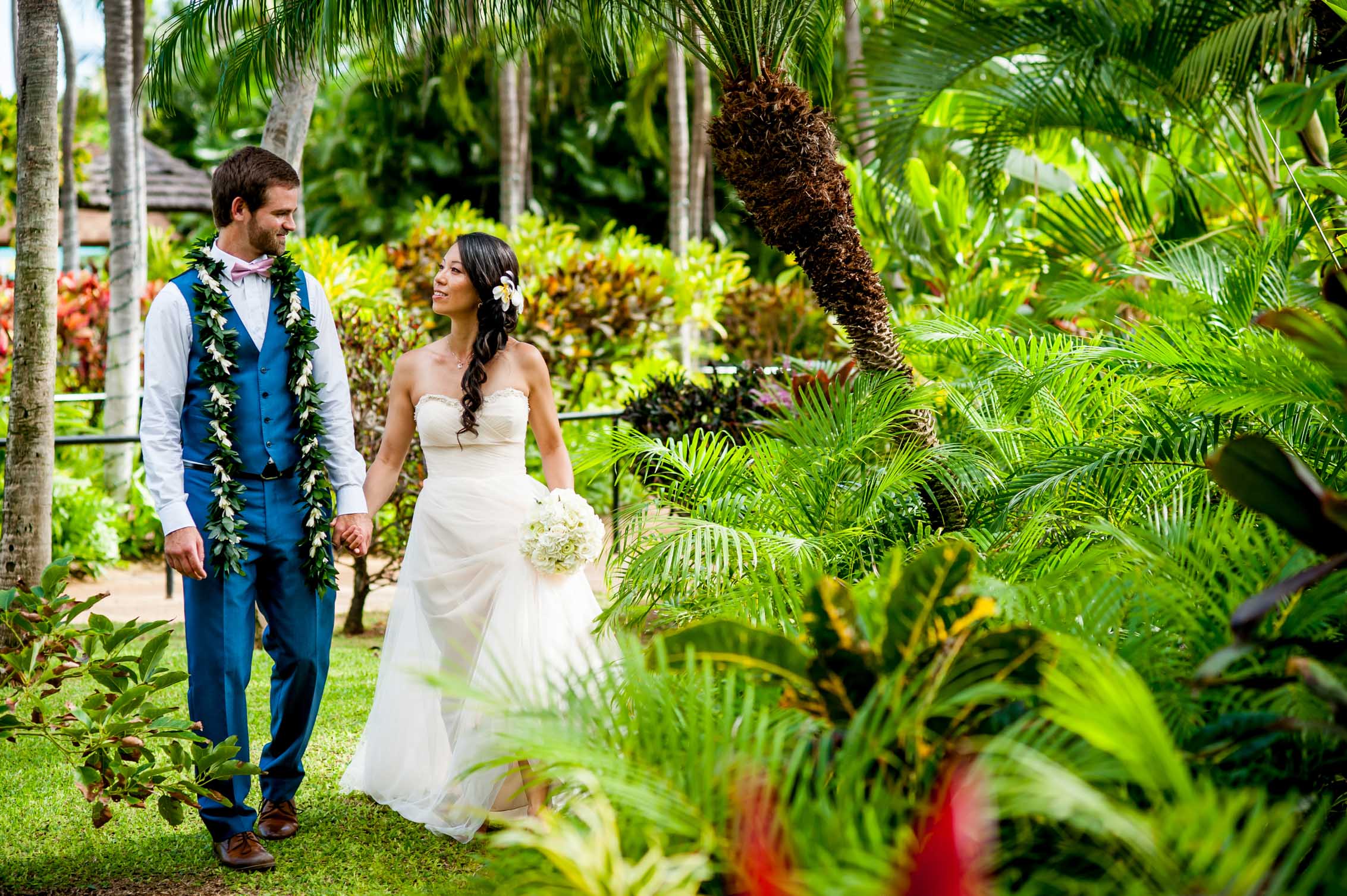 hawaii wedding couple holding hands and walking in lush greenery