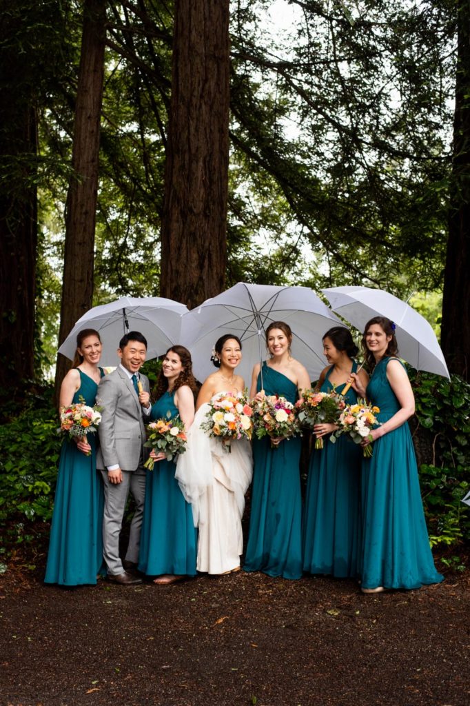 The bride with her bridesmaids and bridesman under white umbrellas